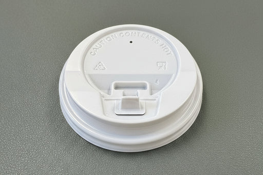White coffee cup lid on a green surface
