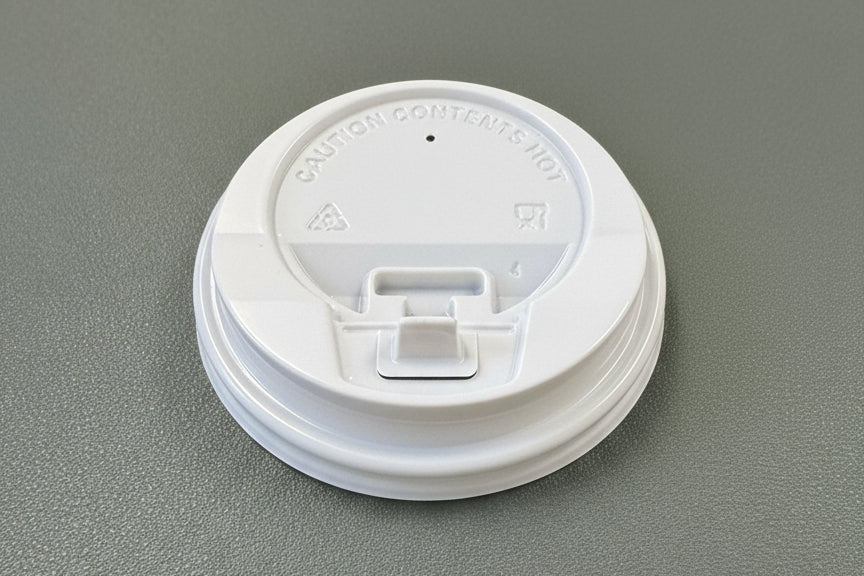 White coffee cup lid on a green surface